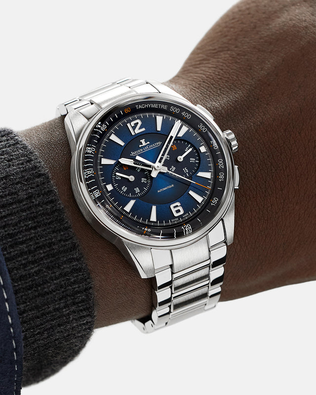 Wearing a Jaeger-LeCoultre Polaris Chronograph, a person with a dark jacket and blue shirt sports this elegant watch on their wrist.